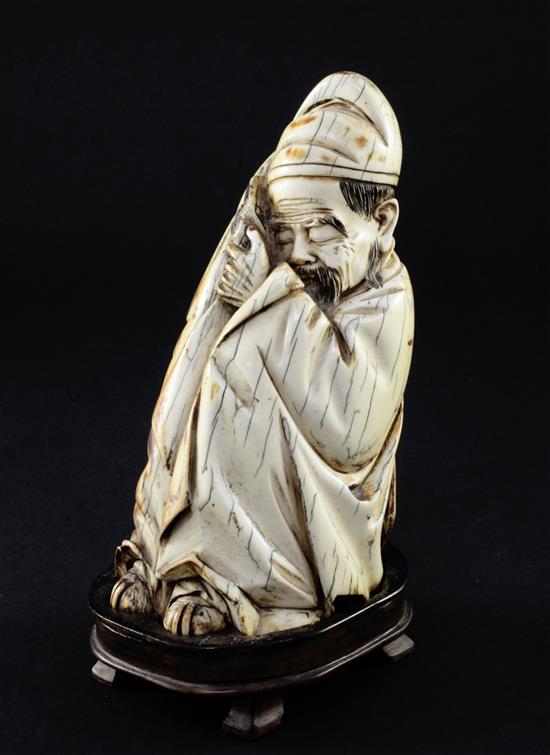 A Chinese mammoth ivory carving of a seated figure of Li Bai, holding a book, 16.5cm, wood stand